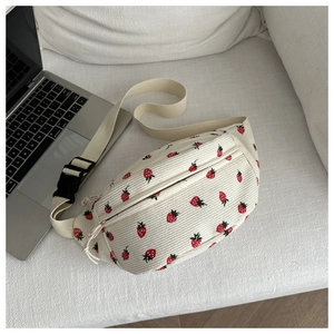 Détail du sac selle en velours côtelé blanc avec imprimé fraises et sangle ajustable