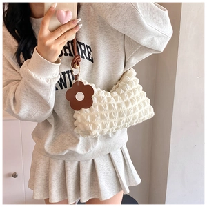 Detailed macro view of white bubble texture fabric shoulder bag with floral pendant charm