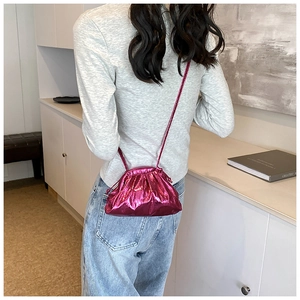 Détail du sac bourse rose métallisé avec texture froncée sur tenue décontractée