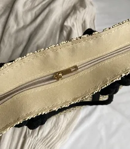 Detalle de la cremallera de metal dorado y el forro de lona beige del bolso tejido