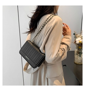 Detail of black quilted chain shoulder bag featuring fashion text and vertical stitching