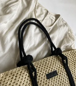 Detalle del bolso de paja tejido a mano con asas de cuerda negra y textura natural