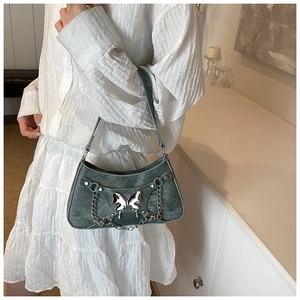 Detalle de bolso de hombro denim gris con mariposa plateada y adornos de cadena