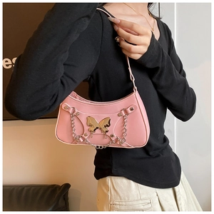 Detalle del bolso de hombro rosa en cuero sintético con lazo plateado y cadenas