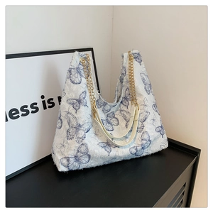 Dettaglio del ricamo a farfalla blu su tessuto bianco di una grande borsa tote con catena