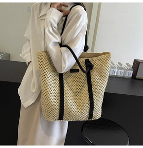 Detalle de bolso tote de paja tejida a mano con asas de cuerda negra y textura rústica
