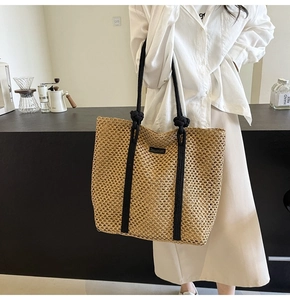 Detalle del bolso tote de tejido calado con asas de cuerda negra y parche de logotipo