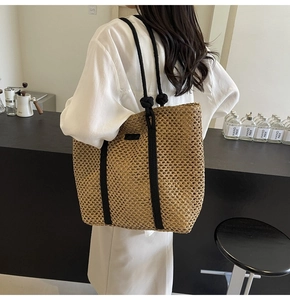 Detalle de bolso tote de paja tejida con asas de cuerda negra y detalles de nudos