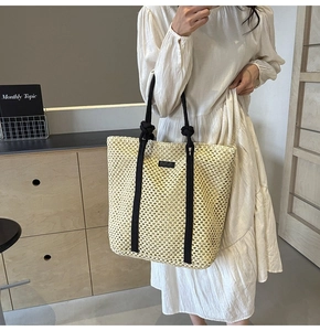Detalle de bolso tote de paja beige con asas de cuerda negras y textura de malla fina