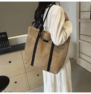 Foto de estilo de vida del gran bolso tote de paja tejida caqui con asas de cuerda negras