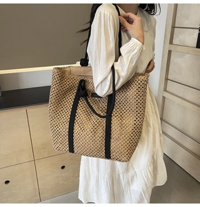 Detalle del bolso tote de paja tejida calada con asa de cuerda negra y forro de tela