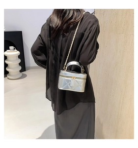 Detailed view of silver quilted mini bucket bag with chain strap on a model's shoulder
