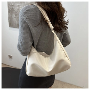 Detail of the cream-white hobo bag with an adjustable strap and metal buckle closure