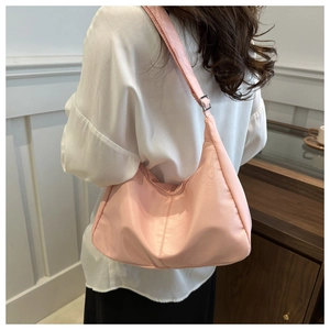 Close-up of a pale pink hobo shoulder bag with an adjustable silver metal buckle strap