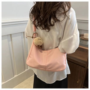 Detailed back view of pink crescent nylon shoulder bag with cute brown plush charm
