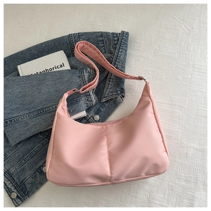 Detailed view of pink nylon shoulder bag with adjustable metal buckle on textured bedding