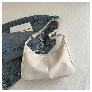 Detail of cream Oxford crescent bag with metal buckle on white textured fabric