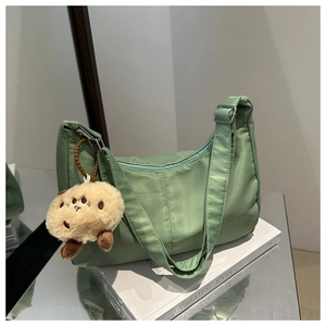 Detail of light green Oxford fabric shoulder bag with cute plush bear charm accessory