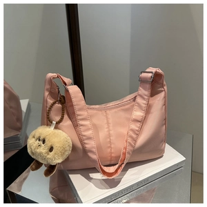 Close-up of pink nylon shoulder bag with zipper and cute beige plush animal charm