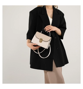 Detail of beige color-block crossbody bag with gold twist lock on silk dress model