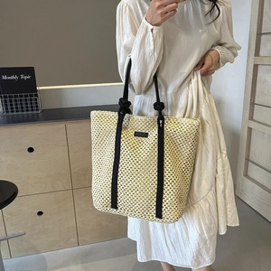 Bolso tote grande de paja trenzada beige con asas de cuerda negra y diseño hueco