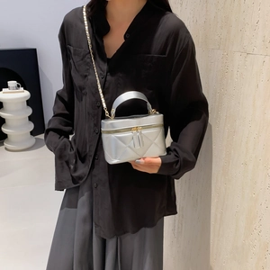 Silver quilted box bag with chain strap shown by a model for a modern fashion look
