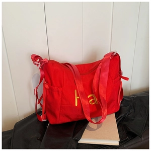 Detail of red nylon tote bag with golden letter print and wide adjustable shoulder strap