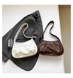 Detail view of white and brown pleated PU leather underarm bags with minimalist texture