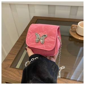 Close-up of a mini pink chain bag with a large silver butterfly buckle and textured fabric