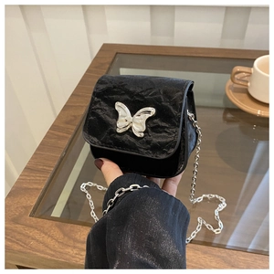 Detailed shot of black mini chain bag with silver butterfly and crinkled texture fabric