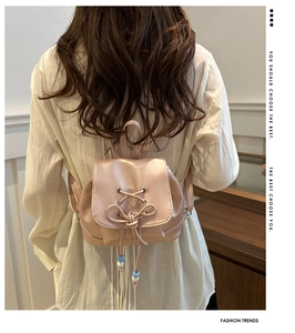 Detail eines rosa metallischen Mini-Rucksacks mit Schleifendekor am Rücken des Modells