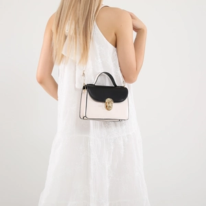 Elegant two-tone crossbody bag with black flap and cream body worn by a model