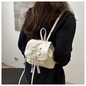 Detailansicht eines beigen Mini-Rucksacks mit Schleife und Perlen-Kordelzug-Details