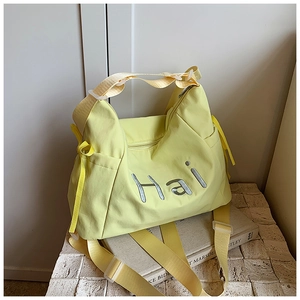 Detail of light yellow nylon tote bag featuring bold Hai letter embroidery and drawstring