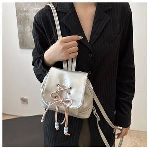 Nahaufnahme eines silbernen Mini-Rucksacks mit rosa Kordelschleife und Perlendetail