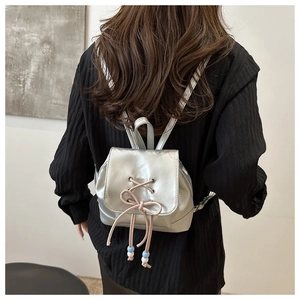 Detail eines silbernen Metallic-Mini-Rucksacks mit rosa Kordelzug-Schleife und Perlen