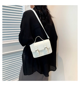 Detail of white vintage crossbody bag featuring classic double buckles and top handle