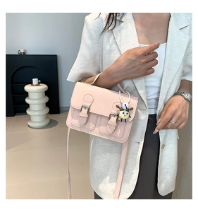 Detailed view of pink mini flap messenger bag with silver buckles and a cute charm accessory