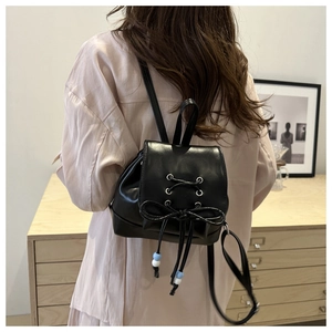 Schwarzer Mini-Lederrucksack mit Schleife und blauen Perlen am Rücken eines Models