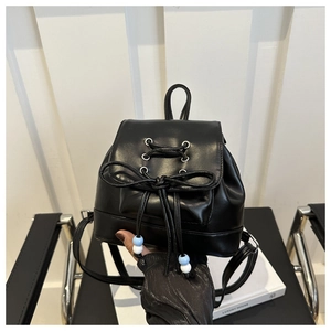 Detail eines schwarzen Mini-Rucksacks aus Leder mit Schleife und silbernen Ösenkordeln