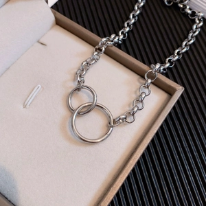 Collier en acier titane avec anneaux doubles entrelacés minimalistes sur fond texturé élégant