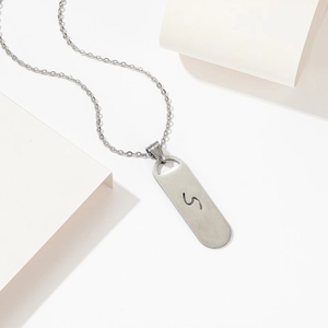 Silver stainless steel skateboard necklace with hollow S letter pendant on a white background