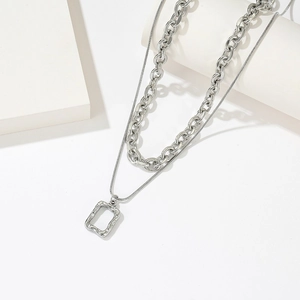 Double-layered titanium steel necklace featuring a textured square pendant on a white block