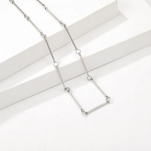 Collier minimaliste en argent à barres géométriques sur un socle blanc pur