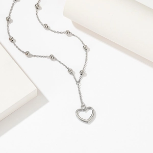 Titanium steel necklace with heart pendant and bead chain on white geometric stand