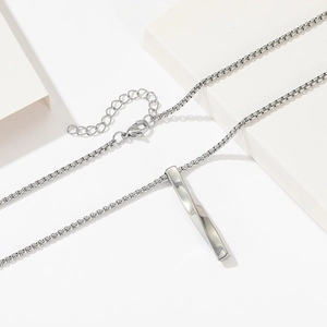 Collier minimaliste en acier titane argenté avec pendentif torsadé sur présentoir