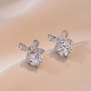 Elegant silver bow earrings with sparkling zircon gemstones on champagne silk