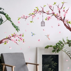 Detalle de vinilos de flores de cerezo rosa con jaula y colibríes sobre pared blanca