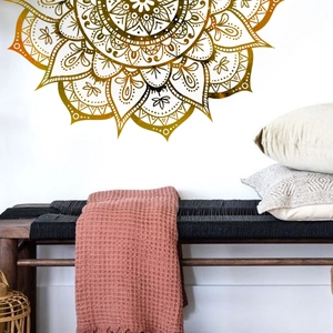 Detail of a large golden mandala wall sticker above a wooden bench in a cozy living room