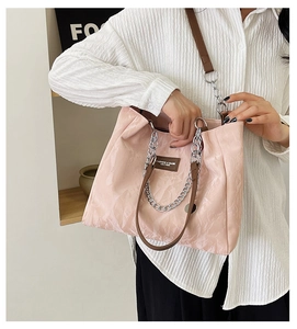 Détail d'un cabas rose clair plissé avec bandoulière en cuir et poignée en chaîne